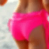 Vibrant neon pink swimsuit bottoms displayed on a sandy beach